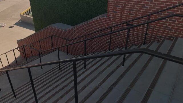 Slow steady pan across wide concrete staircase with brick walls and layered metal railings