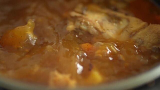 Close-up of pork hock simmering in reddish broth in pot