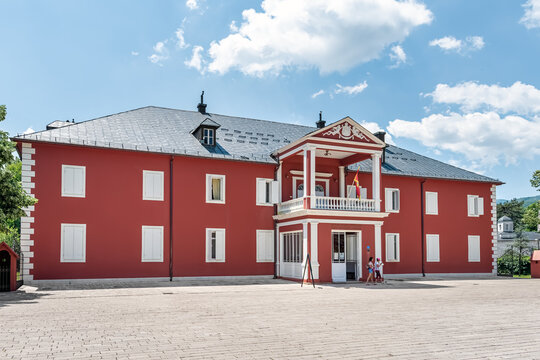 The Cetinje Royal Palace, also known as King Nicholas Museum, with tourists entering the red historic building. This landmark is located on the central Dvorski Trg. Cetinje, Montenegro - June 20, 2021