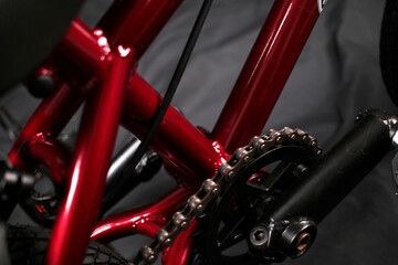 Fototapeta premium Macro shot of a red bicycle frame tube and a metal drive chain.