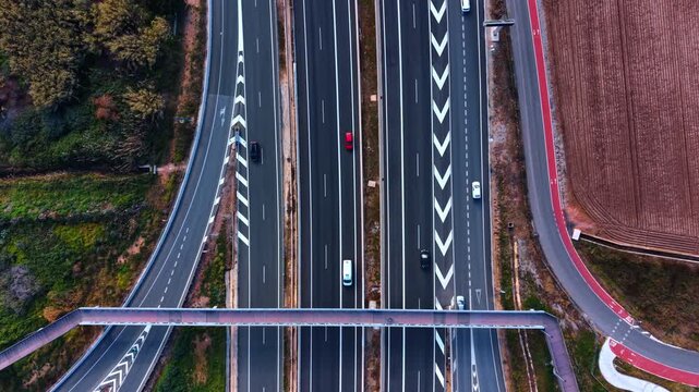 A few parallel highways along the nature landscape. Top view on the roads with moving cars.