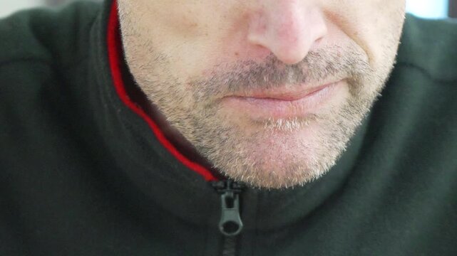 Mouth man chewing extreme close up of a mature man with stubble eating food while wearing a green fleece jacket
