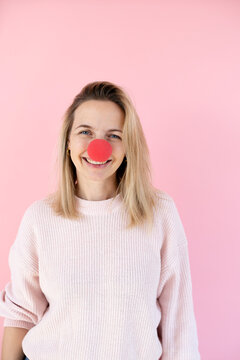 blond woman in front of pink background with red clown nose