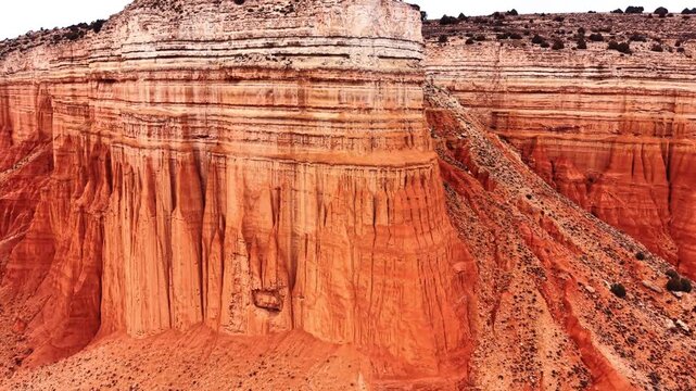 Massive layered rock wall with red and white strata. Detailed view of sedimentary rock formation with prominent red base and horizontal white layers in Spain.