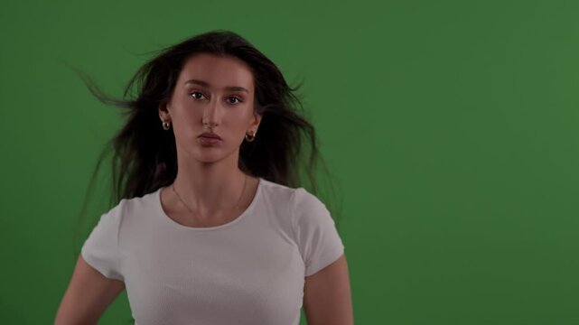 Confidence and self-esteem A young woman poses in front of a green screen her hair blowing in slow motion commercial or editorial projects The clip can be used for advertising marketing.