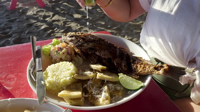 Tourist enjoying traditional fried fish dish on beach in La Libertad, El Salvador, local gastronomy