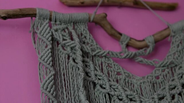 Handmade macrame wall decor on pink rural house wall with traditional woven patterns creating cozy boho atmosphere and authentic countryside interior style