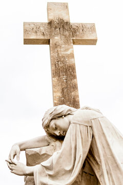 Marble statue of a woman embracing a large marble cross. She expresses sadness, symbolizing the pain of death. Artist unknown, S&atilde;o Jo&atilde;o Batista Cemetery, Rio de Janeiro, Brazil.