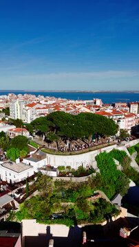 Aerial pull out from Miradouro da Senhora do Monte in Graca with people at viewpoint. Lisbon, Portugal vertical video