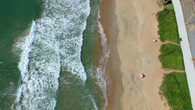 Top down aerial view of ocean waves meeting sandy beach with shoreline patterns in southern Brazil.