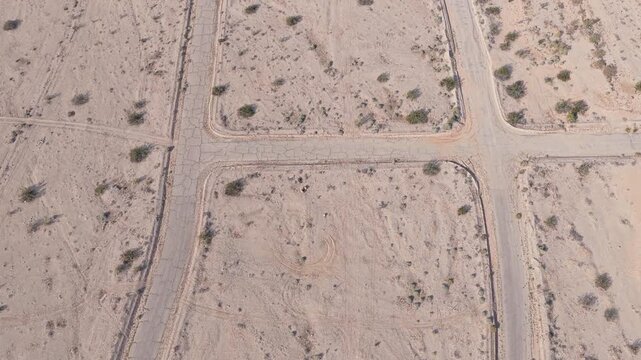 Bird&rsquo;s-eye drone shot slowly flying forward over two parallel abandoned streets in Salton City, California, revealing the quiet layout of this sparsely developed desert community.