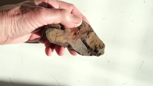 Sensory experience. Ochre stone in woman's hand. Tactile interaction with natural, organic materials. Bright sunlight. Help from digital fatigue.