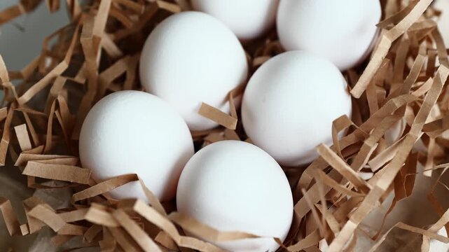 Fresh white eggs lie on a beige on a white surface, ready for cooking.