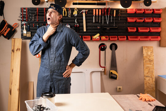 Carpenter man with diy tools for maintenance and repair work suffering sore throat and flu in workshop. Woodworking and carpentry