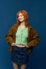 Spring fashion with a young woman and vibrant red hair on a blue background © LIGHTFIELD STUDIOS