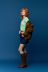 A young woman in a stylish outfit showcases spring fashion against a vivid blue backdrop