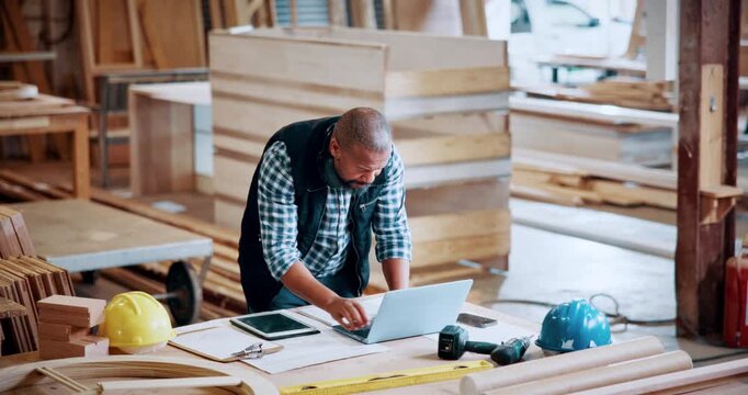 Carpentry, documents and laptop with black man in factory for manufacturing, planning or production. Computer, paperwork and reading with African person in woodworking plant for checklist review