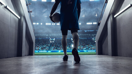 Black Male Soccer Player Walks From the Stadium Tunnel Onto the Pitch Holding the Ball Before a Professional International Football Match, With a Full Arena Set for a Major World Euro Tournament.