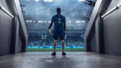Black Male Soccer Player Stands at the Tunnel Entrance Holding the Ball, Facing a Packed Stadium Before Kickoff in a Professional International Football Euro and World Tournament Scene.