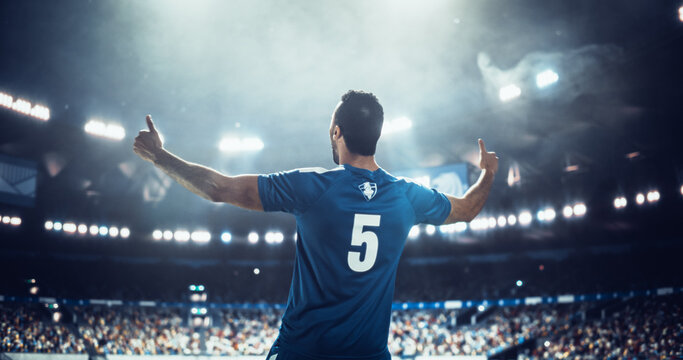 Male Soccer Player Seen From Behind Lifts Both Thumbs on the Pitch Before an International Football Match Game in a Packed World Stadium, Capturing the Scale of a Professional Euro Tournament Event.