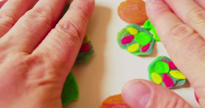 First-person top view of designer laying out abstract design from solid plastic parts prior to applying them, close-up.