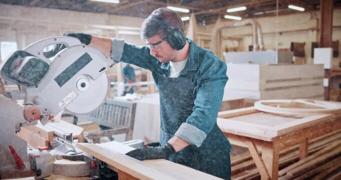 Bandsaw, carpentry and ppe with man in warehouse for manufacturing or production process. Earmuffs, eyewear and sawing machine with person in woodworking plant to resize lumber or timber for project