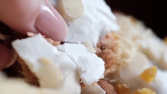 Macro breaking white icing on Easter kulich almond flakes and candied fruit close-up texture crust sweet bread detail