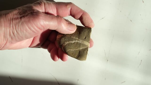 Sensory experience. River pebble stone in woman's hand. Tactile interaction with natural, organic materials. Bright sunlight. Help from digital fatigue.