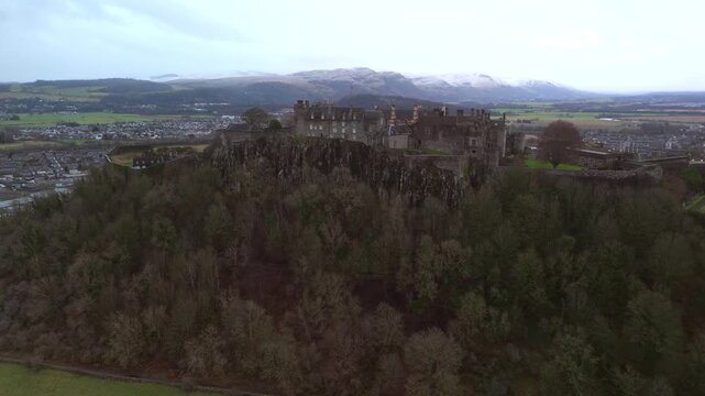 Stirling Scotland city skyline drone flyover and mountains in the distance. Clouds cover the sky, creating an atmosphere in the Scottish highlands