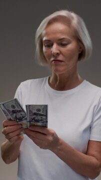 Old Caucasian woman counts the cash one hundred in hands, banknotes. Senior female holds paper money USD dollars in palms, with money deficit. Utility Bills Payment earnings. Elderly lady counting.