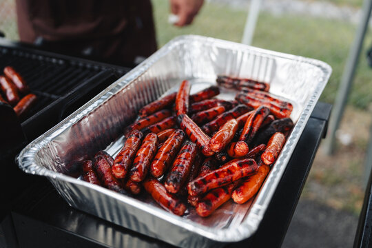 Grilled hot dogs in a foil tray at an outdoor barbecue