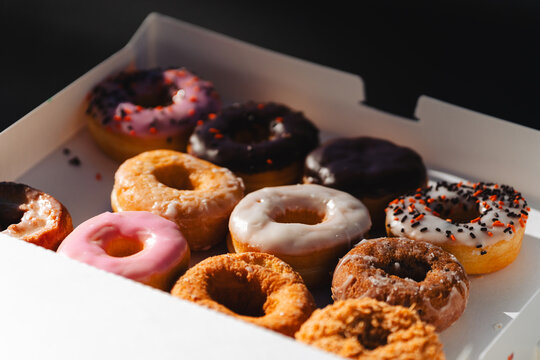 Assorted colorful donuts in a white cardboard box