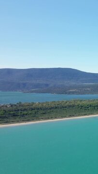 Scenic aerial view of the turquoise waters, sandy beach, and lush green landscape of Isola Varano Nature Reserve in Italy on a clear day.