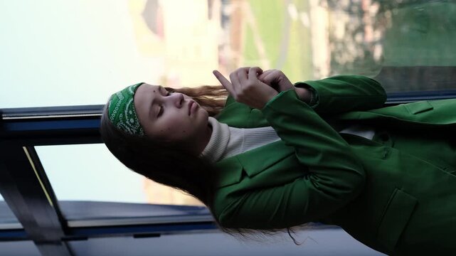 A girl with a bandana looks out the window, her posture conveying a sense of inner struggle and loneliness. The stillness of the scene enhances the mood of detachment, reflection, and quiet sadness