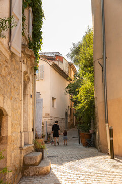 Petite ruelle ensoleill&eacute;e d'un village pittoresque typiquement proven&ccedil;al du sud de la France, pav&eacute;s et maisons anciennes, un p&egrave;re et sa fille marchant dans la ruelle, saison d'&eacute;t&eacute;, La Cadi&egrave;re d&rsquo;Azur