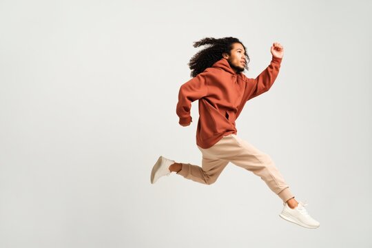 Young man leaping midair in studio against plain background