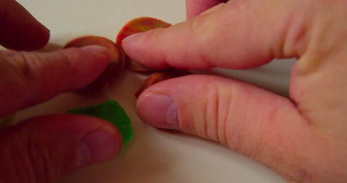 First-person top view of designer laying out abstract design from solid plastic parts prior to applying them, close-up.