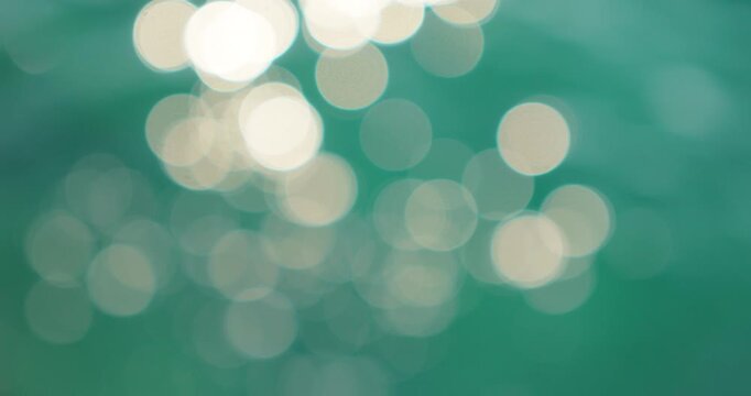 Bright light patterns shimmer on green ocean surface during summer daylight