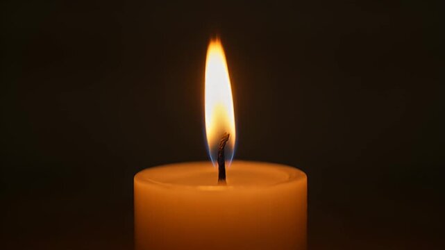 Single candle flame against a dark background creating warm ambiance and mood
