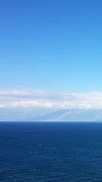 Calm blue sea under a clear sky with distant mountains on the horizon, captured near Koroni, Greece. Peaceful seascape ideal for travel and nature concepts.