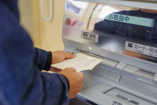銀行ATMで通帳記帳を行う利用者