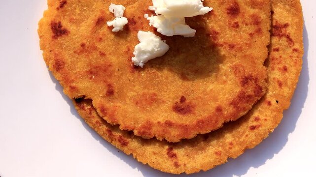 Traditional Punjabi cuisine Makki Ki Roti and Saag with butter served in ceramic bowl and plate. Top view shot of popular north Indian Punjabi food Makki Ki Roti and Sarson ka Saag rotating on a turnt
