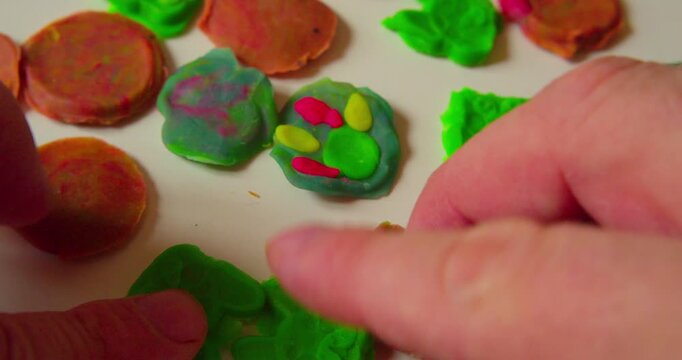 Hands of a designer placing abstract design composed of solid plastic fragments on a surface, first-person perspective, close-up.