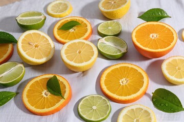 Fototapeta premium Colorful assortment of fresh citrus fruits on a light fabric, showcasing oranges, lemons, and limes.