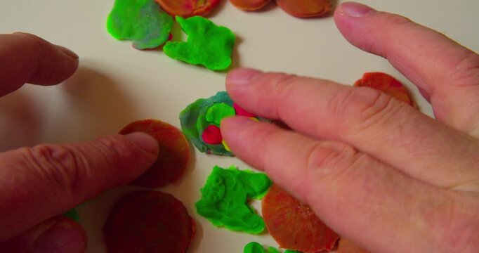 First-person top view of designer laying out abstract design from solid plastic parts prior to applying them, close-up.