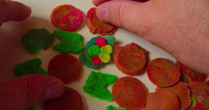 Designer arranging abstract pattern from hardened plastic pieces on a surface before transferring it, first-person top view, close-up.