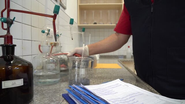 Scientist performs titration experiment in laboratory with distillation equipment