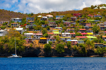 Fototapeta premium Case-Pilote is a town and municipality in the French overseas department of Martinique. A panoramic view from a whale-watching boat of the coastline, featuring numerous colorful homes with ocean views