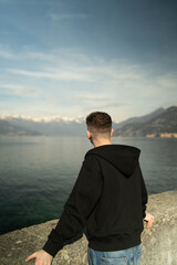 Fototapeta premium Traveler standing back view looking at Alpine mountains and Lake Como landscape in Lombardy Italy.