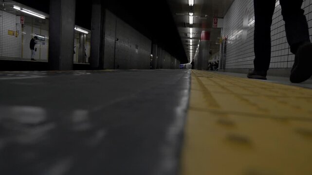 Low angle view of empty subway platform with lone figure waiting for approaching train